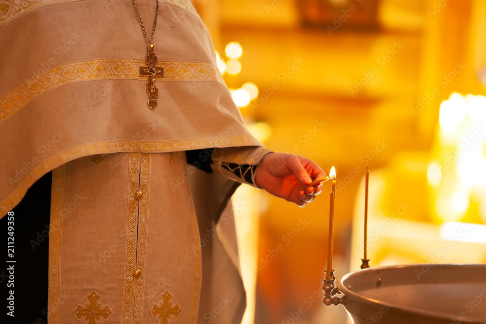 Christening ceremony in the Orthodox church, priest lighting candles at