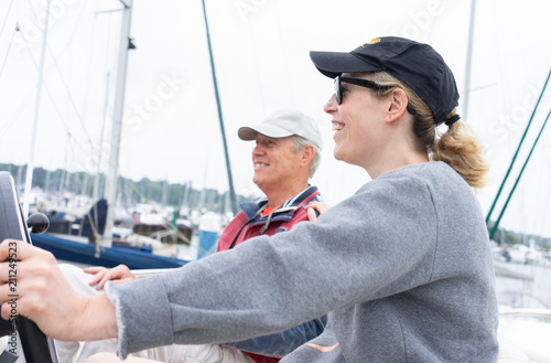 Daughter driving a motor cruiser out to sea with her father
