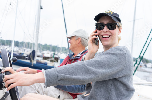 Woman at the helm of a motor cruiser on her mobile phone laughing