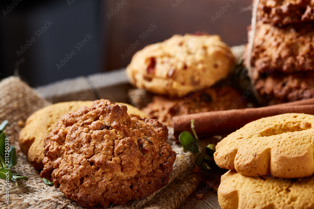 Conceptual composition with assortment of cookies and cinnamon on a wooden barrel, selective focus, close-up Conceptual composition with assortment of cookies and cinnamon on a wooden barrel, selective focus, close-up