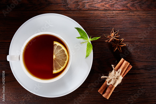 Overhead view of a cup of tea with cinnamom, mint leaves and fruits of star anise. Close-up photo. photo