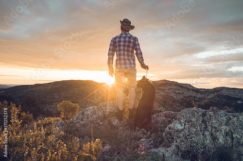 Mountaineer with his dog in the mountains.guy and dog at sunset