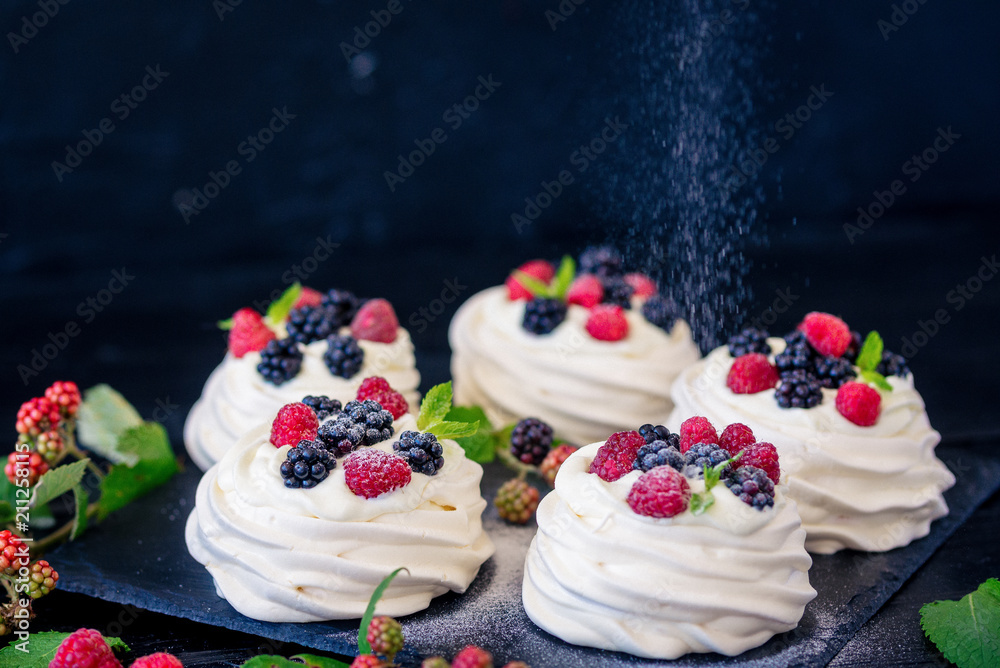 Homemade meringue basis for cake Pavlova with fresh blueberries and BlackBerry and powdered sugar on black concrete texture background. Copy space Homemade meringue basis for cake Pavlova with fresh blueberries and BlackBerry and powdered sugar on black concrete texture background. Copy space