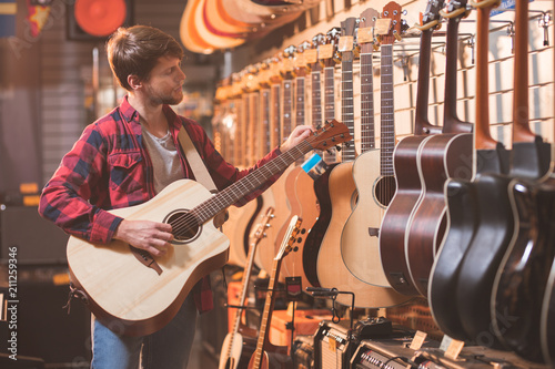 Young man with guitar in a music store