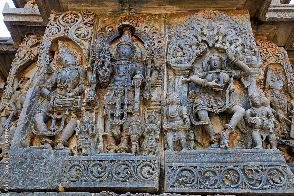 Ornate wall panel reliefs depicting from left Deity playing damaru, Vishnu and dancing Sarswati, Hoysaleshwara temple, Halebidu, Karnataka