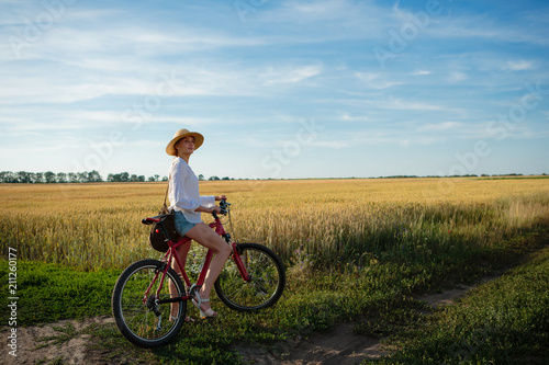 Fototapeta Naklejka Na Ścianę i Meble -  Woman on bike in wheat fields