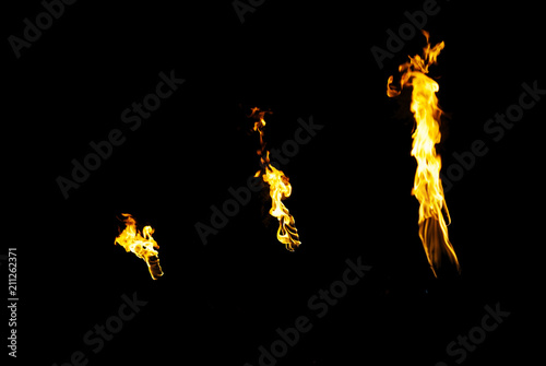 three flames of a torches in the dark on a black background, only the fires is visible