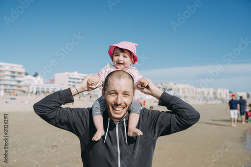 France, La Baule, portrait of father carrying his little daughter on shoulders on the beach photo