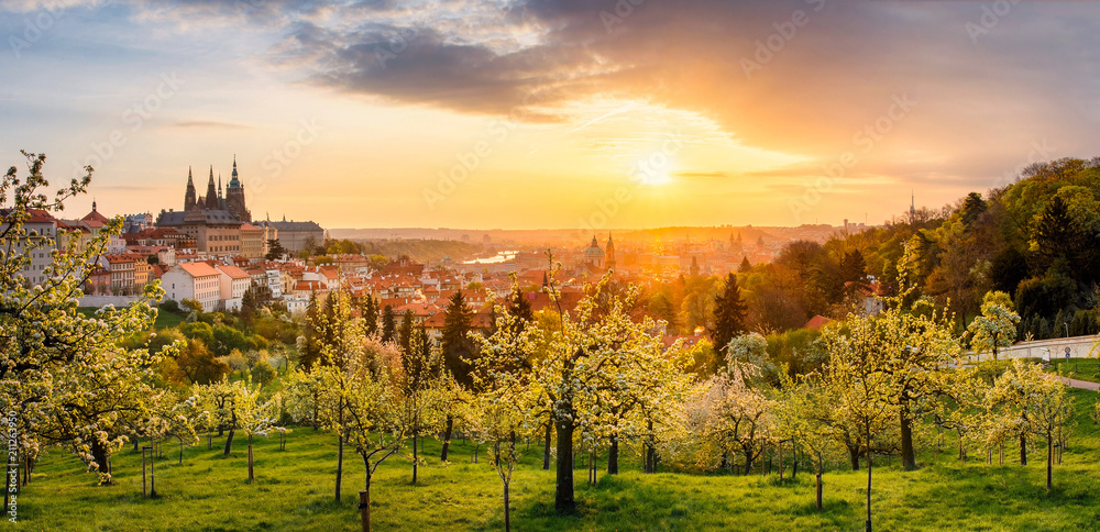 A beautiful spring view of Prague at sunrise from Petrin hill. Prague Castle and St. Vitus Cathedral on the left and a golden rising sun in the background.