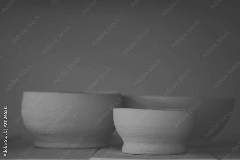 Ceramic clay products stand on the shelf close-up. Sculptor sculpts pots products from white clay. Dark. Workshop pottery. Master crock. Cultural traditions. Handmade. Craft. Twisted potter's wheel. Ceramic clay products stand on the shelf close-up. Sculptor sculpts pots products from white clay. Dark. Workshop pottery. Master crock. Cultural traditions. Handmade. Craft. Twisted potter's wheel.