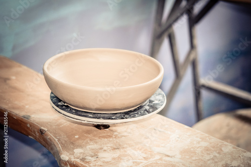 Ceramic clay products stand on the shelf close-up. Sculptor sculpts pots products from white clay. Dark. Workshop pottery. Master crock. Cultural traditions. Handmade. Craft. Twisted potter's wheel.