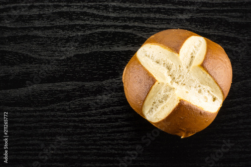 Bavarian bread bun top view on black wood background one fresh baked loaf.