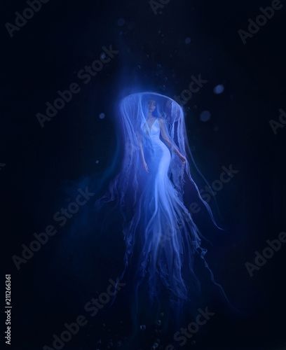 A jellyfish girl floating in levitation on a dark ocean floor. A beautiful, white dress and a hat with tentacles fluttering about the water. Space, alien creation. Art photo. © kharchenkoirina