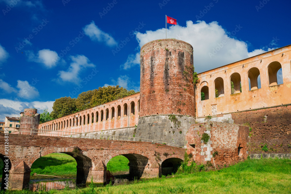 Pisa ancient walls public park with bridge, moat and tower with old city red flag symbol of the medieval republic