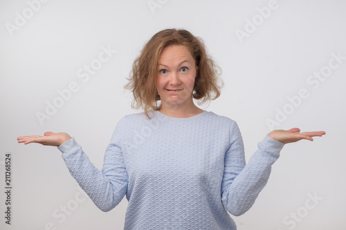 Shrugging norwegian woman wearing blue sweater in doubt doing shrug.