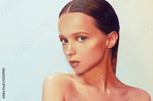 Fashion portrait of young elegant girl. Paslet background, studio shot. Beautiful brunette woman with gold lips and golden bright makeup, nails. Woman with stylish hair and make.Face portrait closeup. photo