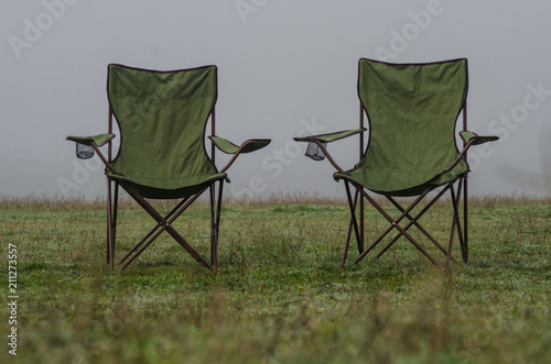 Two tourist chairs stand on the grass