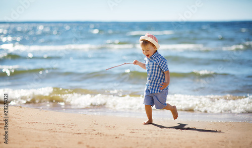 Boy walking at sea in straw hat