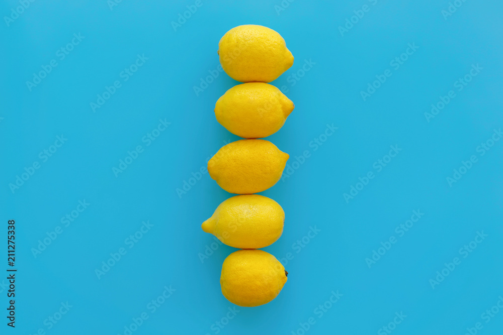 yellow lemons in line on bright blue paper, trendy flat lay. fruits modern image, top view. juicy summer vitamin and diet concept. pop art style. creative minimalism. space for text yellow lemons in line on bright blue paper, trendy flat lay. fruits modern image, top view. juicy summer vitamin and diet concept. pop art style. creative minimalism. space for text