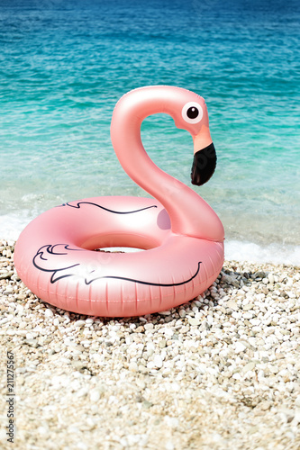 giant inflated flamingo on a beach with turquois water of Ionian Sea Albania © allasimacheva