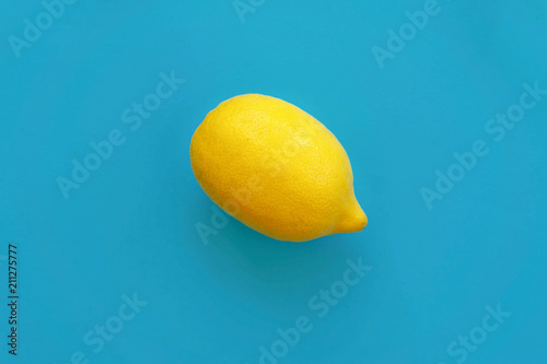 bright yellow lemon on blue paper flat lay. trendy stylish background, fruit top view. space for text photo