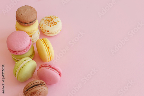 food photography of tasty colorful macarons on trendy pastel pink paper. space for text pink, yellow, green, white, brown macaroons. yummy background. diet concept. luxury catering