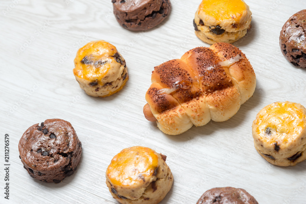 closeup delicious sausage bread roll and fresh tasty scones on wooden table closeup delicious sausage bread roll and fresh tasty scones on wooden table