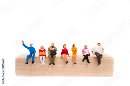 Miniature people sitting on wooden block isolated on white background using as business and social concept