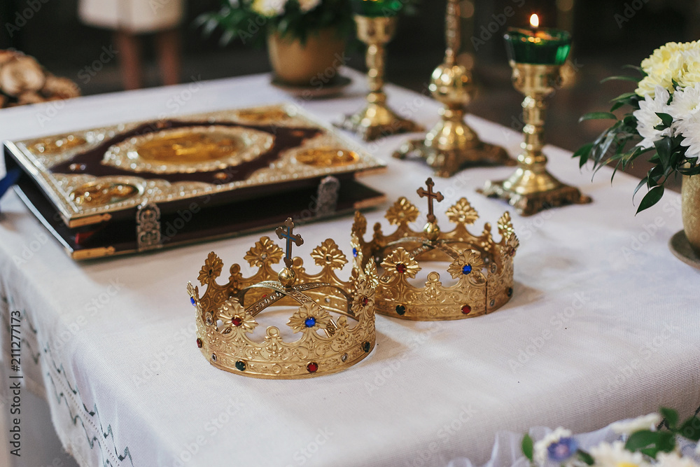 golden crowns and bible on holy altar during wedding ceremony in church. spiritual moments of holy matrimony golden crowns and bible on holy altar during wedding ceremony in church. spiritual moments of holy matrimony