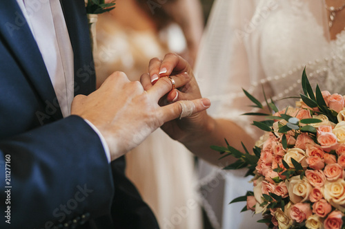 beautiful bride and groom hands exchanging wedding rings in church during wedding ceremony. spiritual holy matrimony. wedding couple and priest putting on rings photo