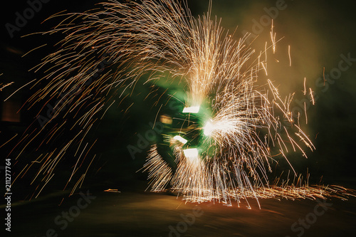 Fire dancers swing, spinning green fire and man juggling with bright sparks in the night. fire show performance and entertainment. amazing fire show at night at festival or wedding party