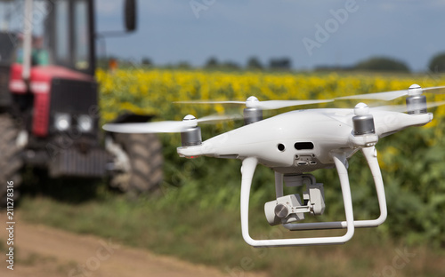 Drone in front of tractor in sunflower field