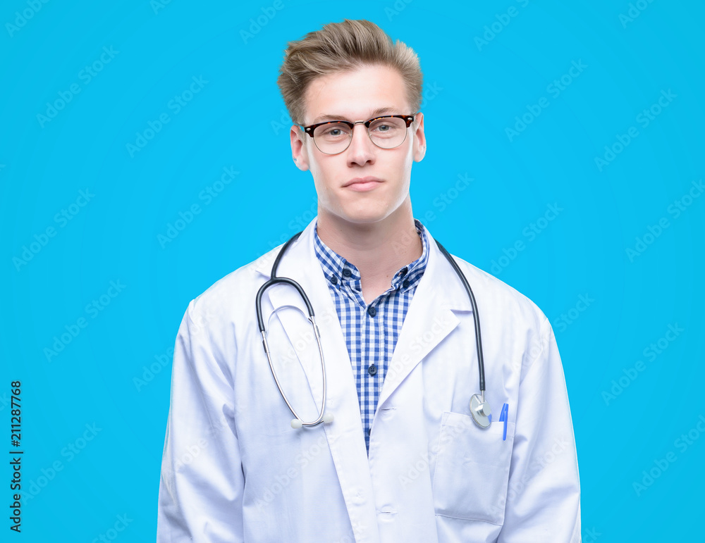 Young handsome blond doctor with a confident expression on smart face thinking serious Young handsome blond doctor with a confident expression on smart face thinking serious