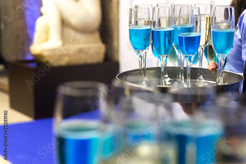 The waiters greet guests with alcoholic drinks. Champagne, blue wine, white wine on trays.