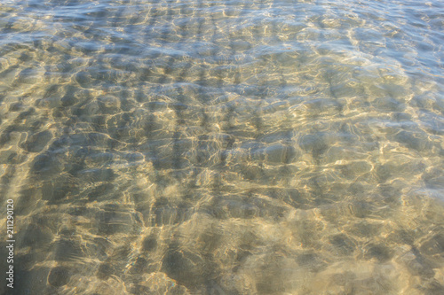 Sandy seabed through transparent sea water . Crystal clear waters background