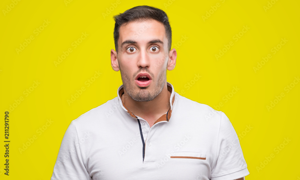 Handsome young casual man wearing white t-shirt scared in shock with a surprise face, afraid and excited with fear expression