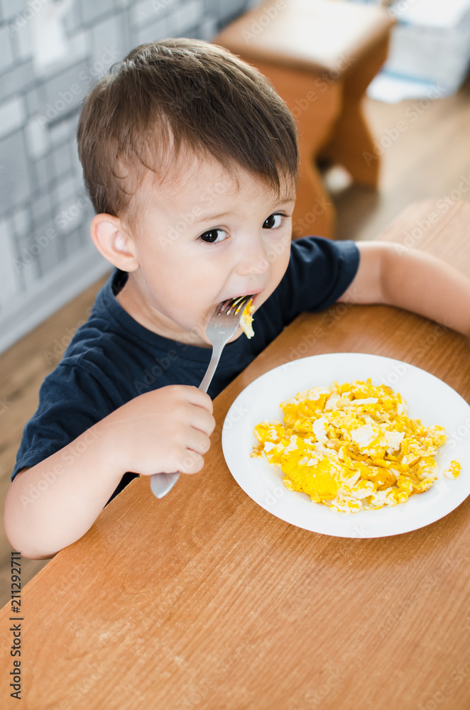 the child greedily in the kitchen eating an omelet in the afternoon in the summer the child greedily in the kitchen eating an omelet in the afternoon in the summer