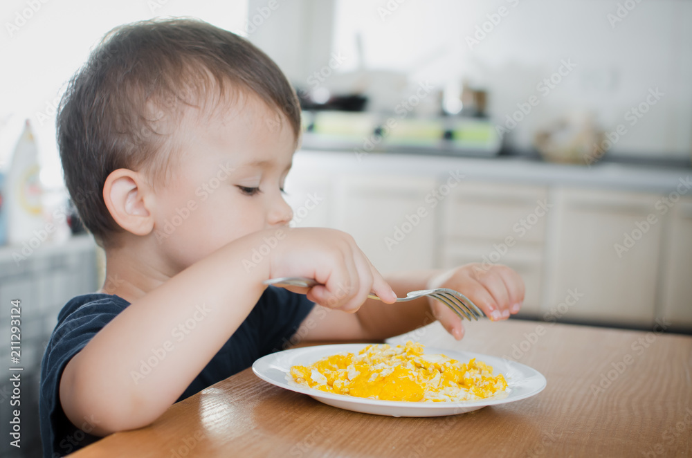 the child greedily in the kitchen eating an omelet in the afternoon in the summer the child greedily in the kitchen eating an omelet in the afternoon in the summer