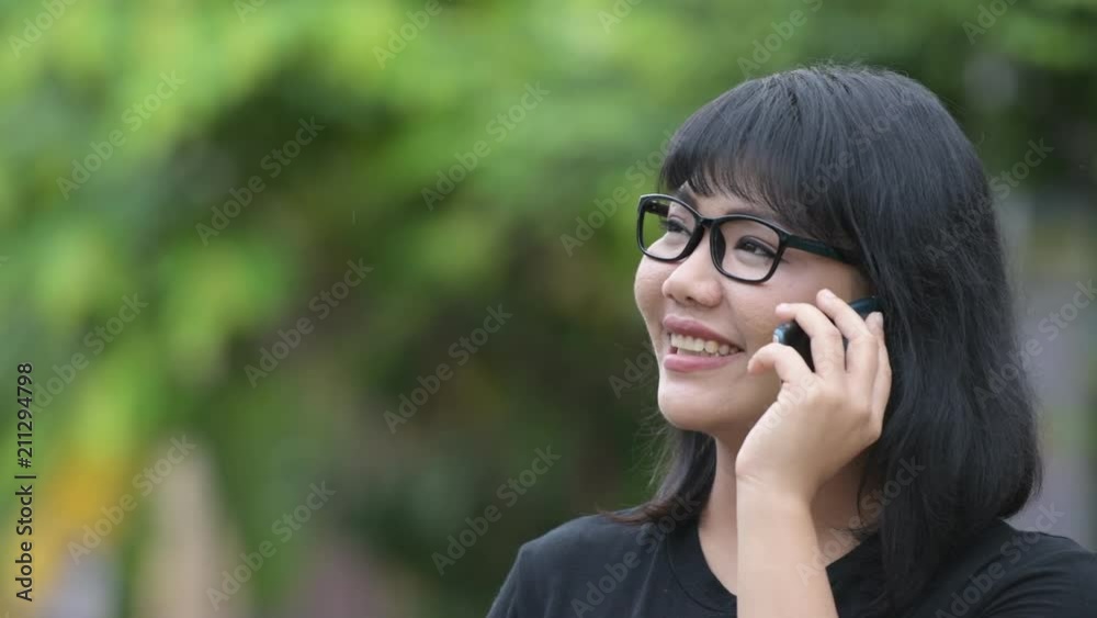Beautiful happy Asian businesswoman talking on phone in the streets outdoors Beautiful happy Asian businesswoman talking on phone in the streets outdoors