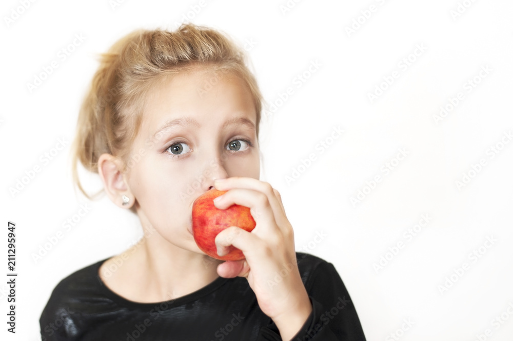 A girl eating delicious red peach with pleasure on a white background. She really loves fruit, more than meat products A girl eating delicious red peach with pleasure on a white background. She really loves fruit, more than meat products