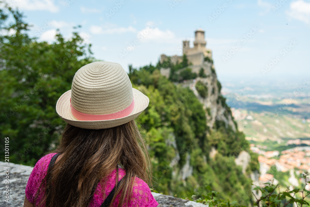 A beautiful touristic girl in the San Marino, admiring the castle on the mountain
