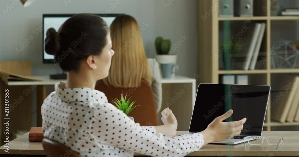 Back view of the Caucasian woman working on the laptop computer while it being attacked by virus and has error writing on the screen. Indoors. Back view of the Caucasian woman working on the laptop computer while it being attacked by virus and has error writing on the screen. Indoors.