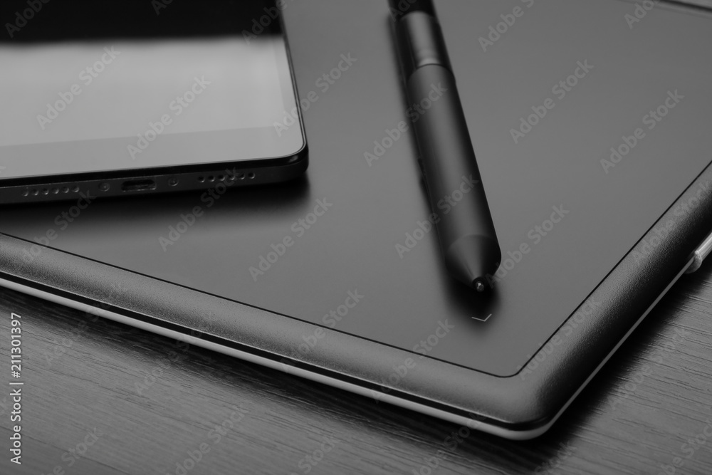 Graphic tablet with stylus and smartphone on a wooden table Graphic tablet with stylus and smartphone on a wooden table