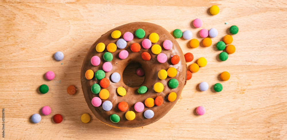 Donut chocolate glaze and sprinkles, top view and isolated, wooden table background. Donut chocolate glaze and sprinkles, top view and isolated, wooden table background.