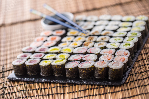Collection of Sushi maki on slate board with soy sauce and chopsticks