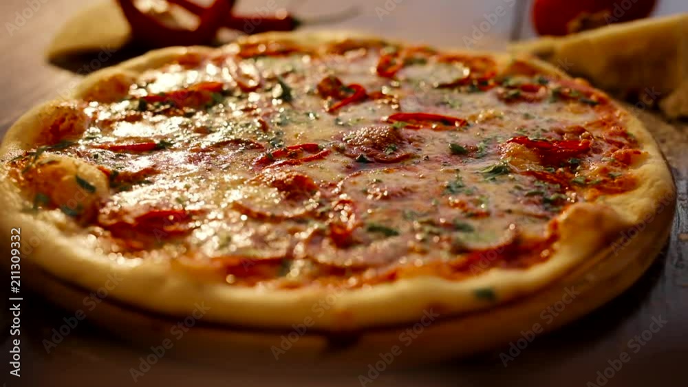 Close up of Well Baked Pizza with Salami, Fragrant Herbs, Melted Cheese. Fresh Vegetables, Tasty Sauce. Typical Italian Food on the Wooden Plate. Appetizing Pizza. Delisious Dish. Close up of Well Baked Pizza with Salami, Fragrant Herbs, Melted Cheese. Fresh Vegetables, Tasty Sauce. Typical Italian Food on the Wooden Plate. Appetizing Pizza. Delisious Dish.