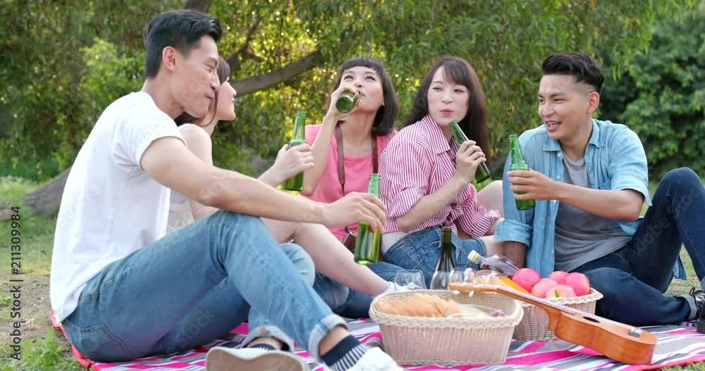 Young asian Friends go picnic together and enjoy the wine