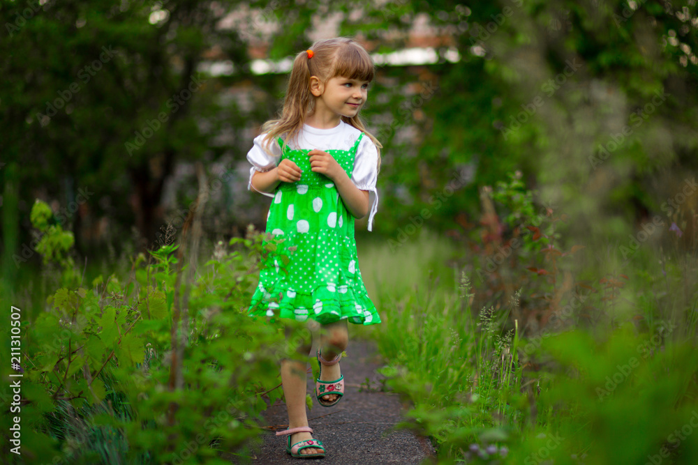 Little girl walk in green garden in sunny summer day Little girl walk in green garden in sunny summer day