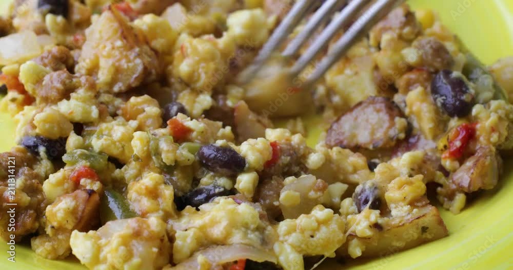 Close video of stirring a scrambled eggs breakfast meal with a fork on a yellow plate. Close video of stirring a scrambled eggs breakfast meal with a fork on a yellow plate.