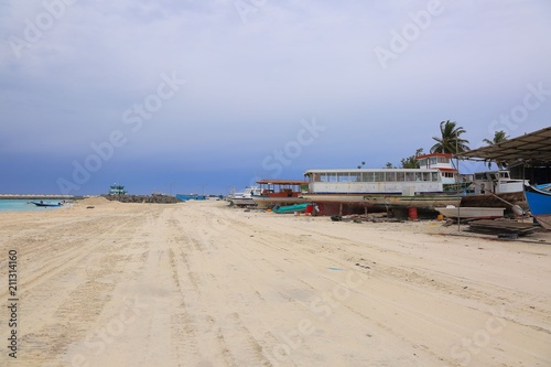 Industrial area on Dhangethi Island, Maldives. Sand road, old boats on blue sky background.